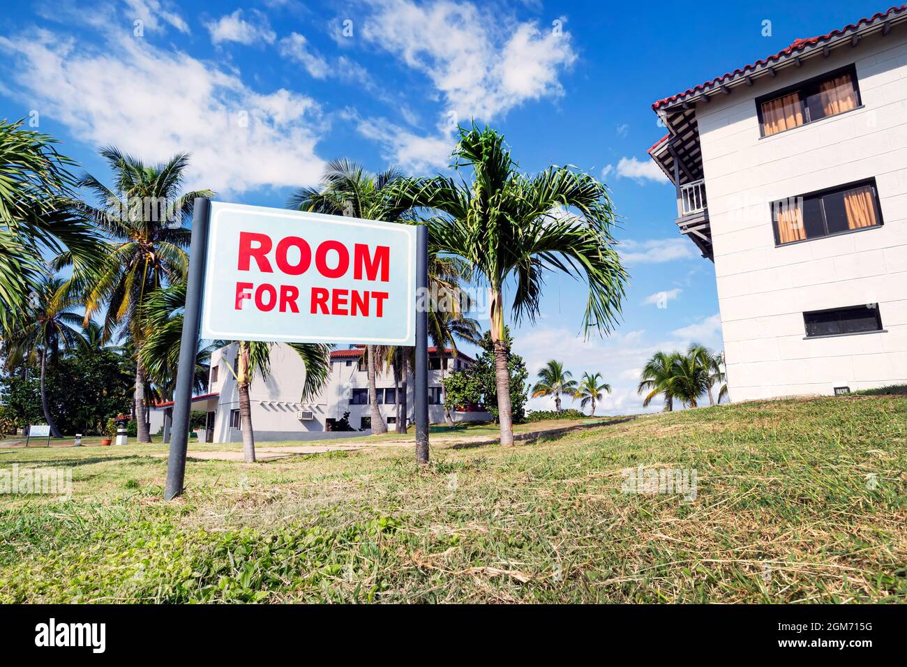 Cartello con testo ROOM IN AFFITTO vicino a un edificio moderno nella campagna rurale. Affitto di case e camere in una bella zona di villeggiatura vicino alla costa Foto Stock