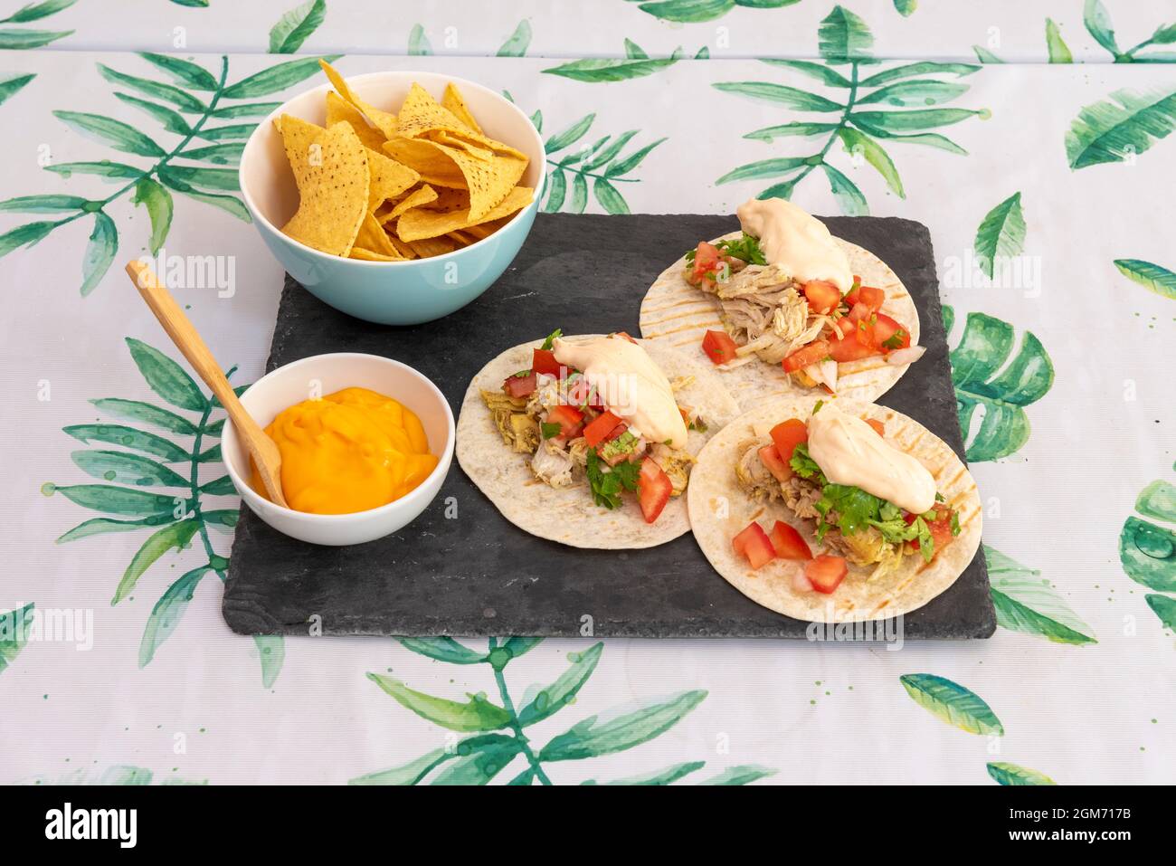 Menu messicano con tre tinga di pollo e nachos di mais in una ciotola per immergere con formaggio cheddar fuso Foto Stock Menu messicano con tre tinga di pollo e nachos di mais in una ciotola per immergere con formaggio cheddar fuso Foto Stock