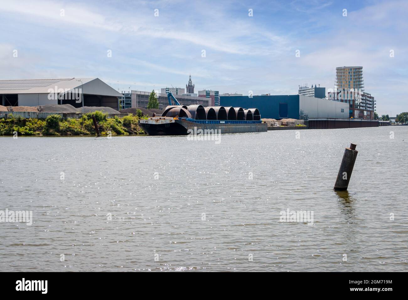 Nave da trasporto carica di enormi tubi di ferro in un porto industriale vicino al fiume chiamato 'Maas' con base nella città di Roermond, provincia di Limburgo Foto Stock