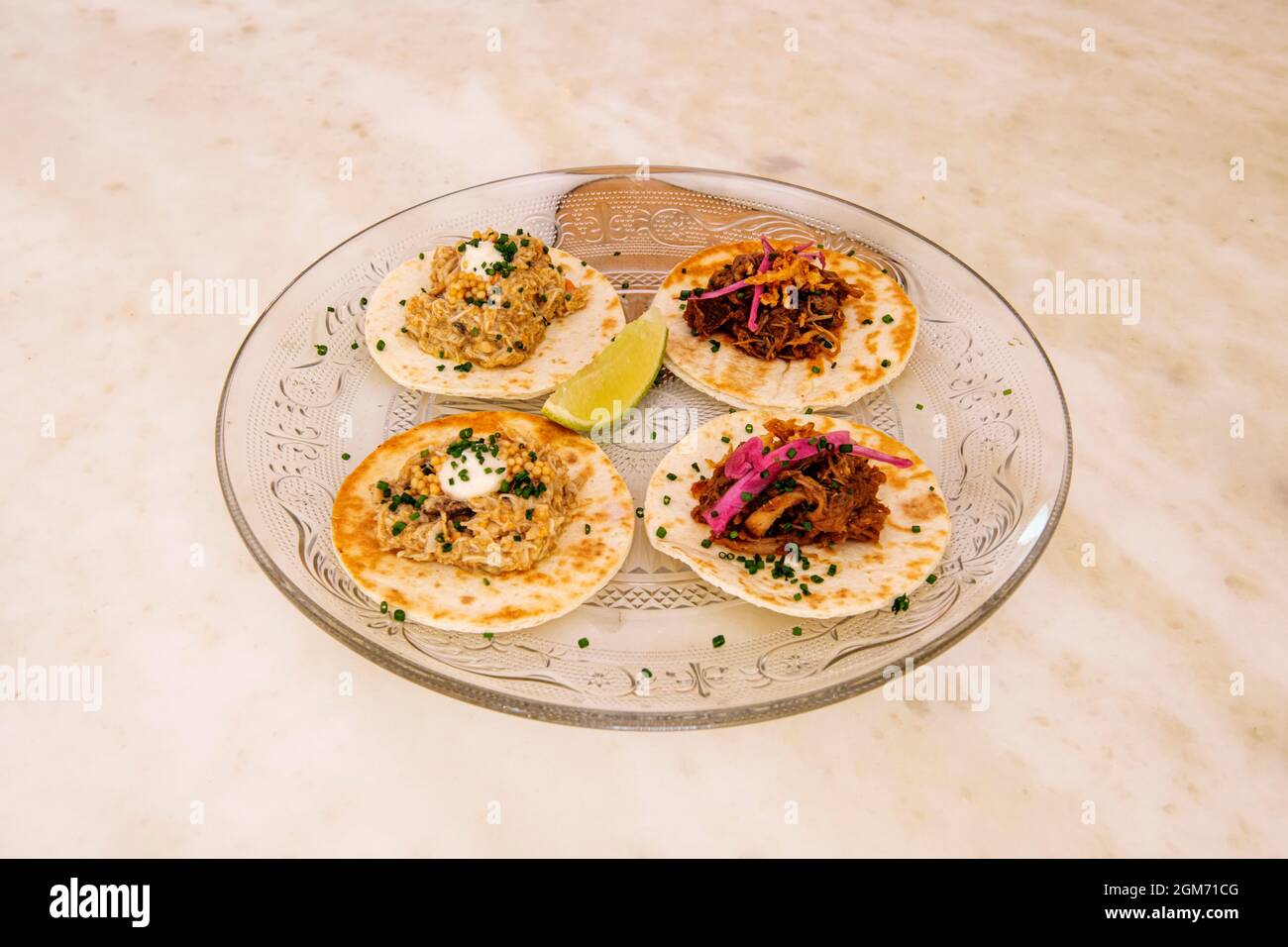 Quattro tacos di due sapori. Pollo tinga e cochinita pibil su un piatto di vetro Foto Stock