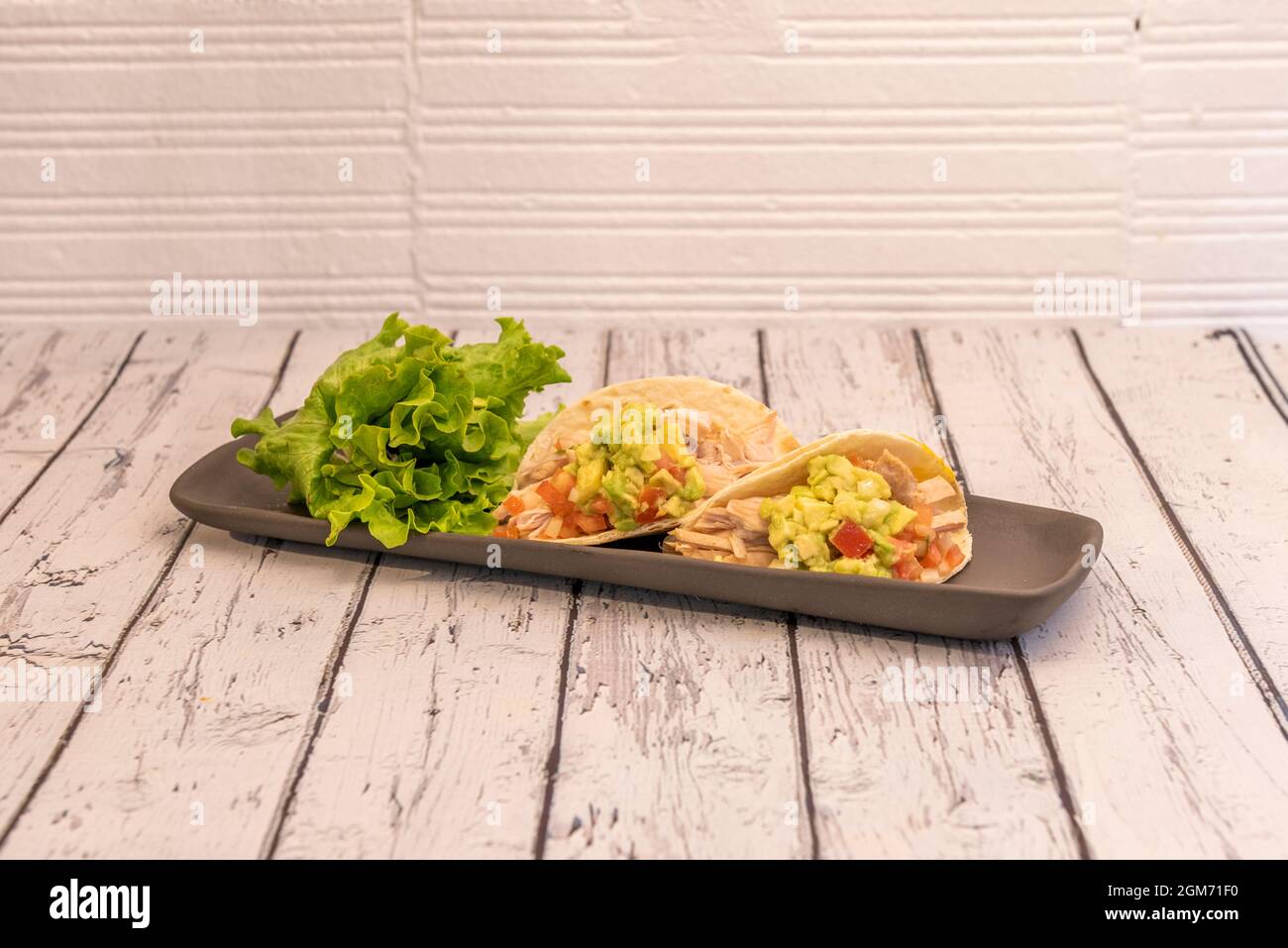 Due tacos messicani di carne di pollo stufata con guacamole di avocado, lattuga e pezzi di pomodoro con cipolla Foto Stock Due tacos messicani di carne di pollo stufata con guacamole di avocado, lattuga e pezzi di pomodoro con cipolla Foto Stock
