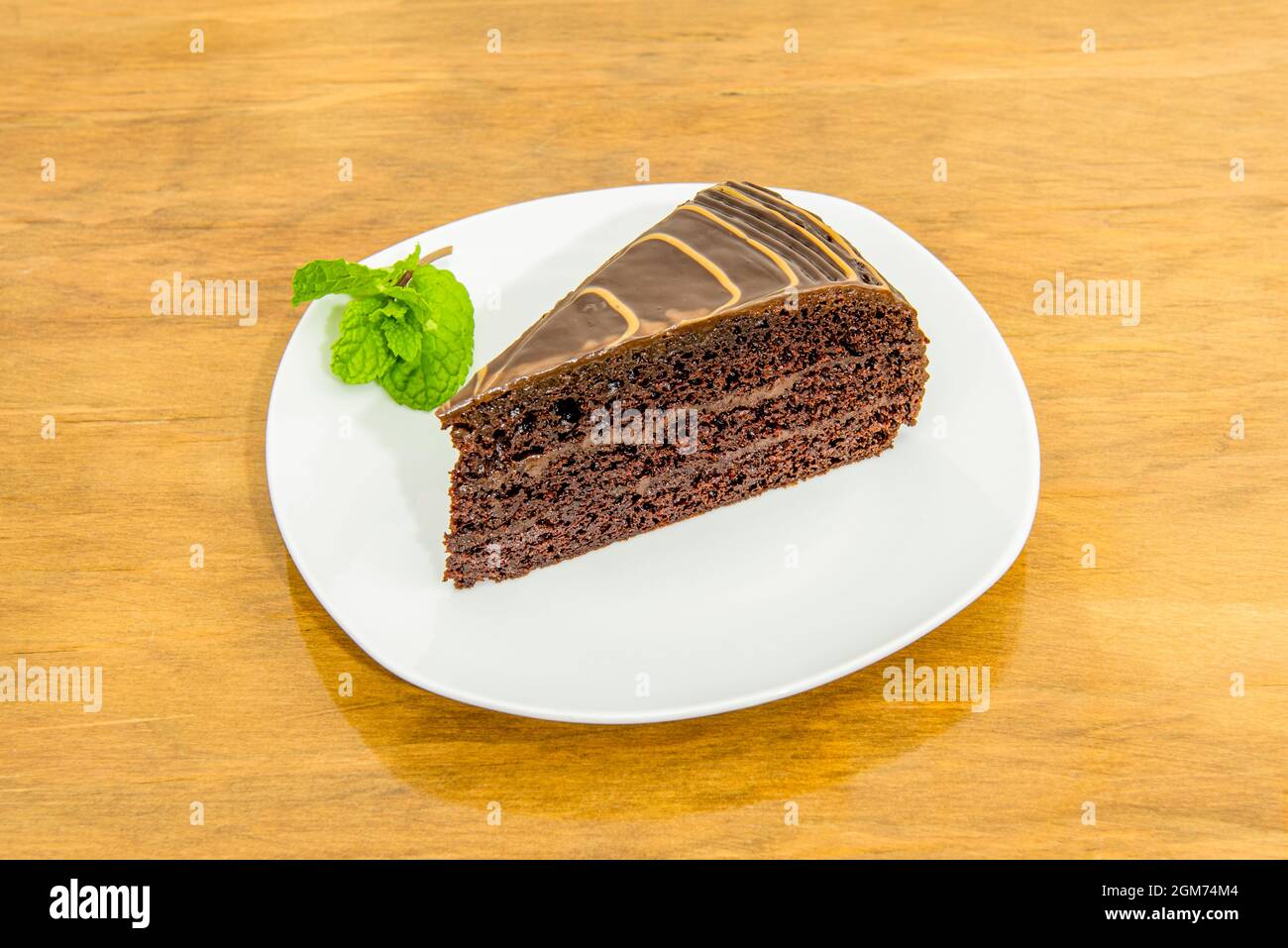 Porzione di delizioso dolce al cioccolato con tre strati di pan di Spagna con rivestimento di cioccolato lucido Foto Stock