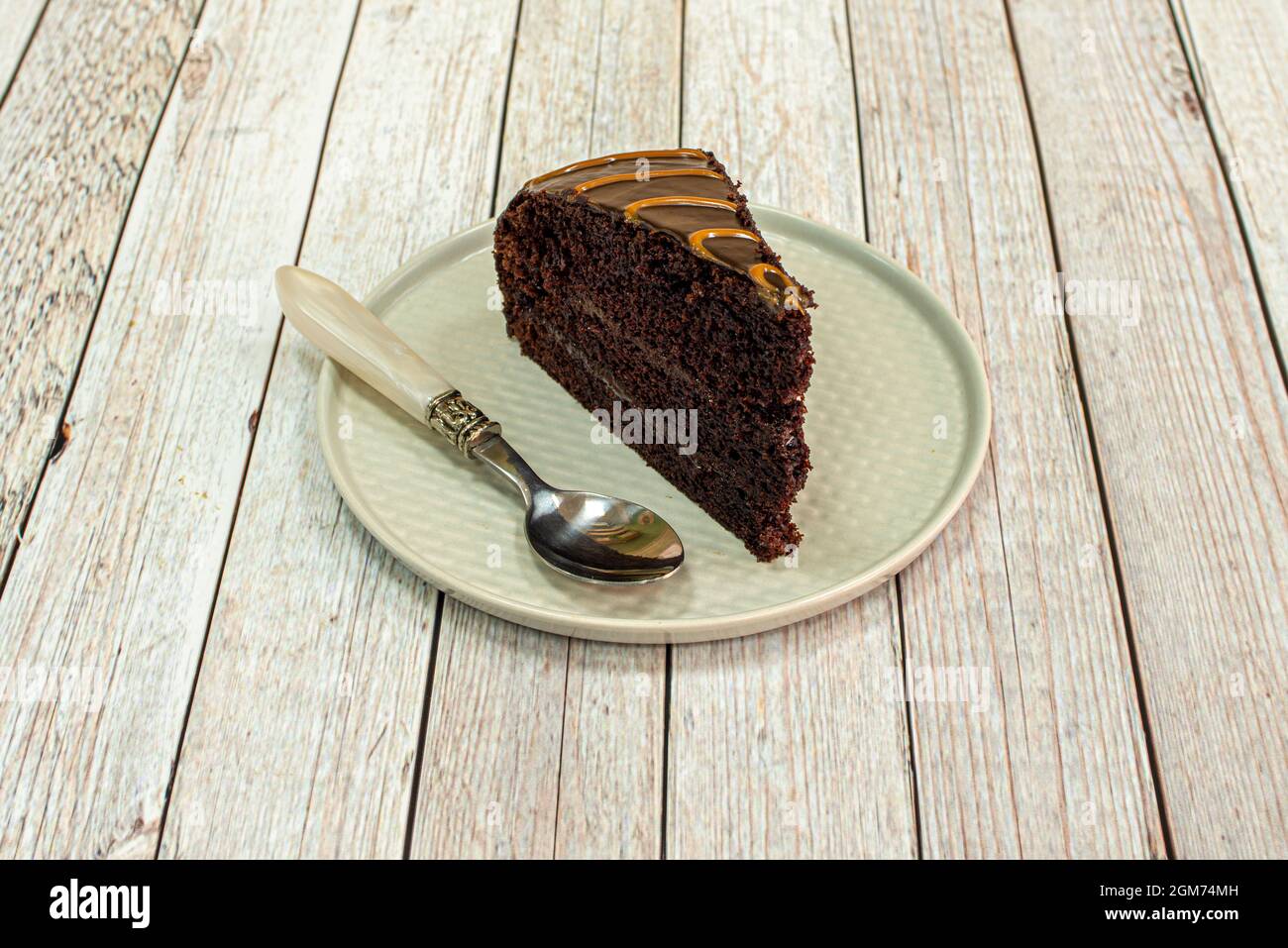 Porzione di deliziosa torta al cioccolato con un cucchiaio d'annata su un piatto grigio Foto Stock