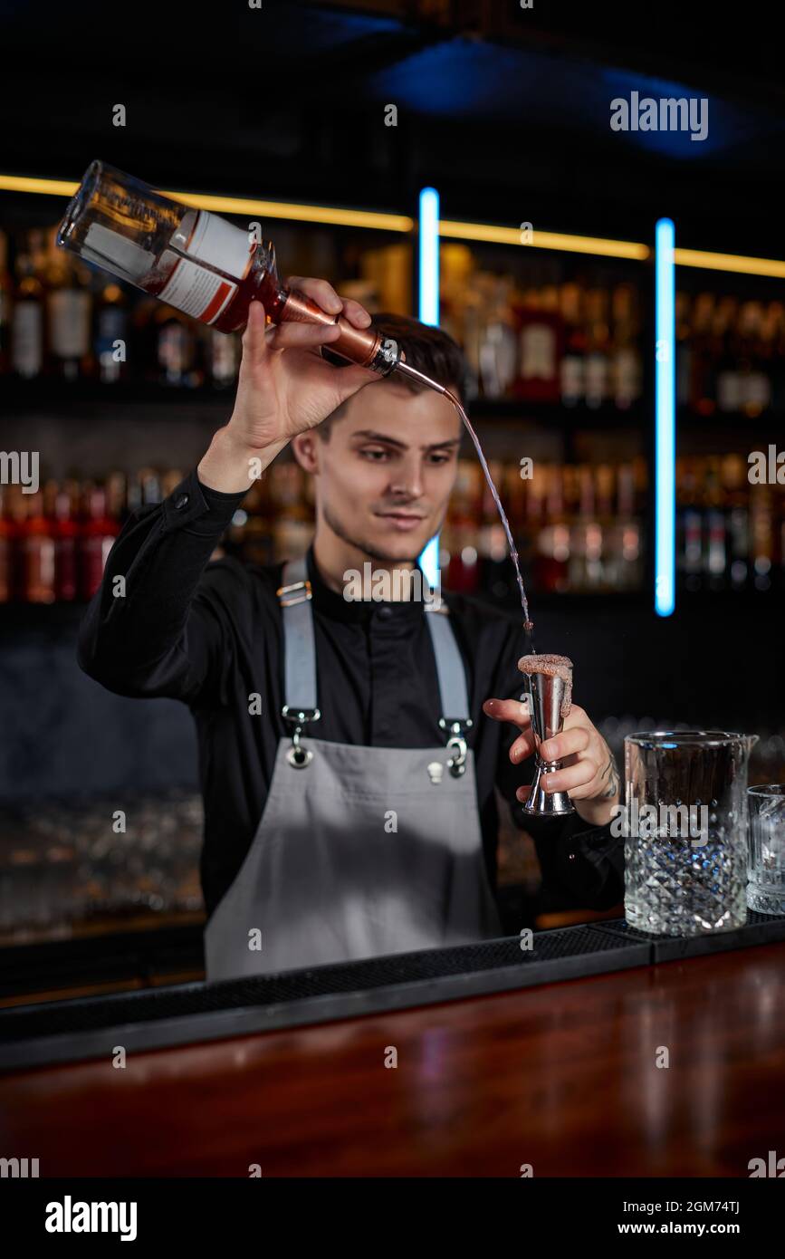 Barman in grembiule aggiunge l'ingrediente al vetro Foto stock - Alamy