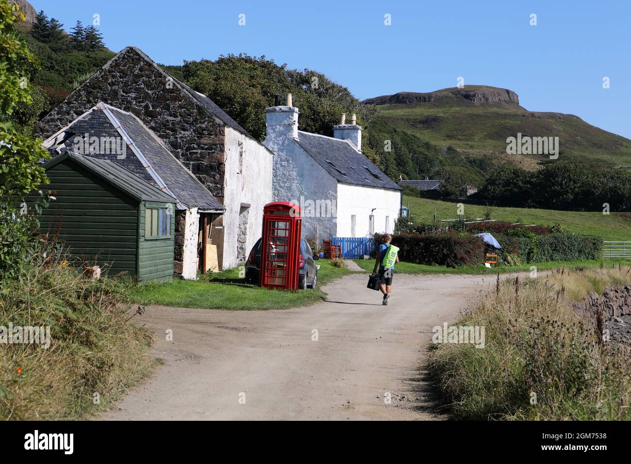 Isola di canna, tranquilla strada principale sull'isola nelle Ebridi interne della Scozia. L'ufficio postale è il capannone verde dietro la scatola del telefono. Foto Stock