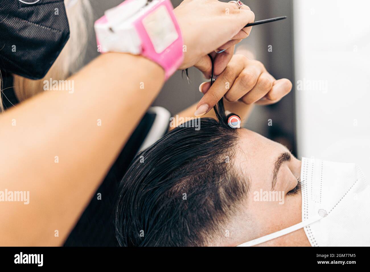 Parrucchiere applicazione di un rullo ai capelli di un cliente con maschera per arricciare i capelli Foto Stock