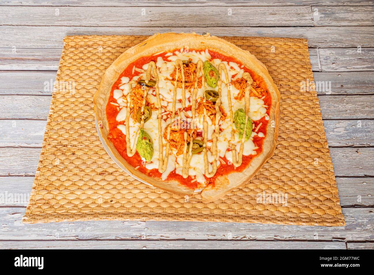 Ricetta per pizza Tex mex con guacamole, carne di pollo tinga e jalapeños con mozzarella con pomodoro e pasta di farina di ceci Foto Stock
