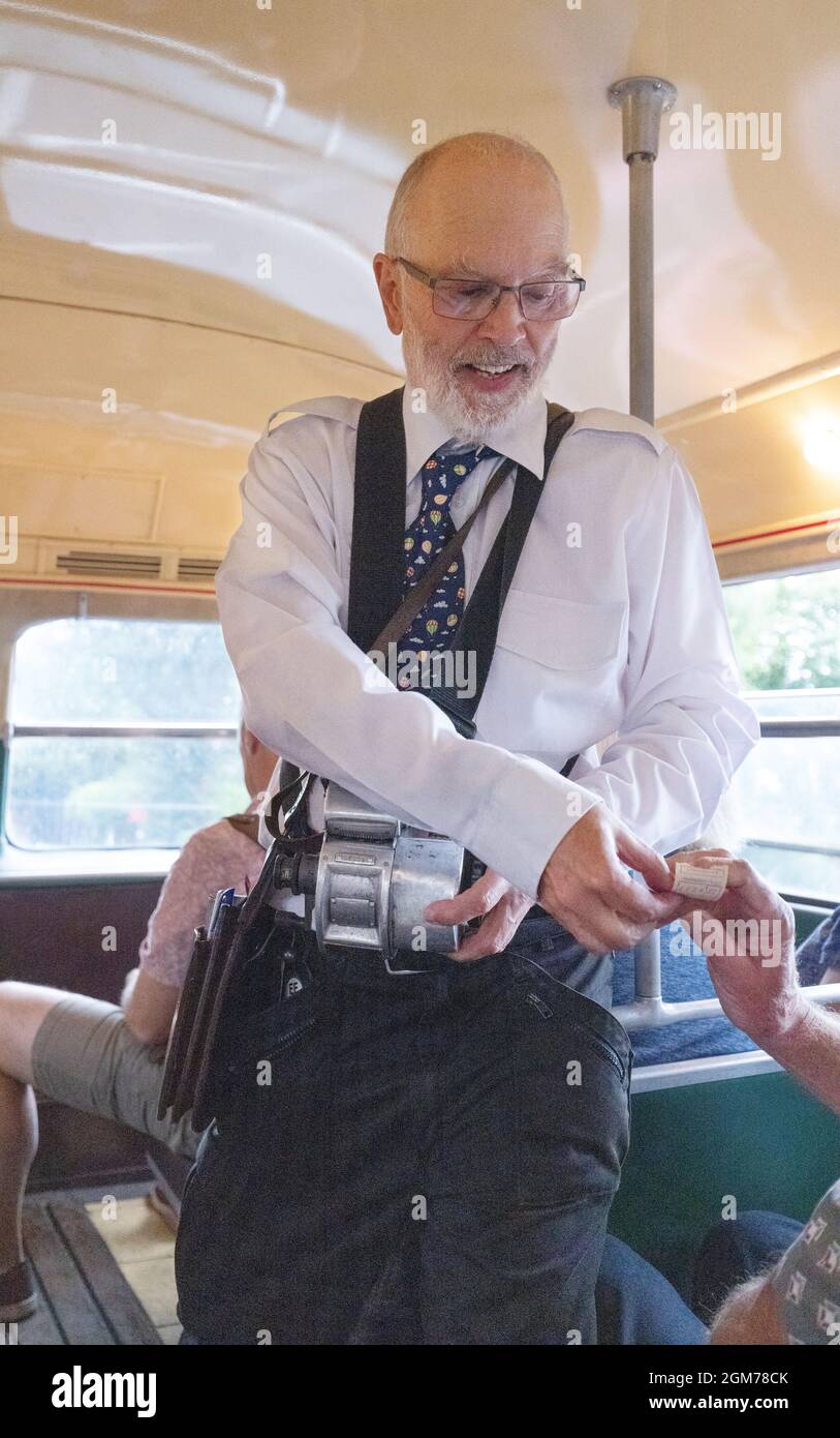 Oggi (2021) ricreazione di un direttore d'autobus degli anni '60 che consegna i biglietti a persone su una macchina d'autobus d'epoca, Epping-Ongar Railway, Essex UK Foto Stock