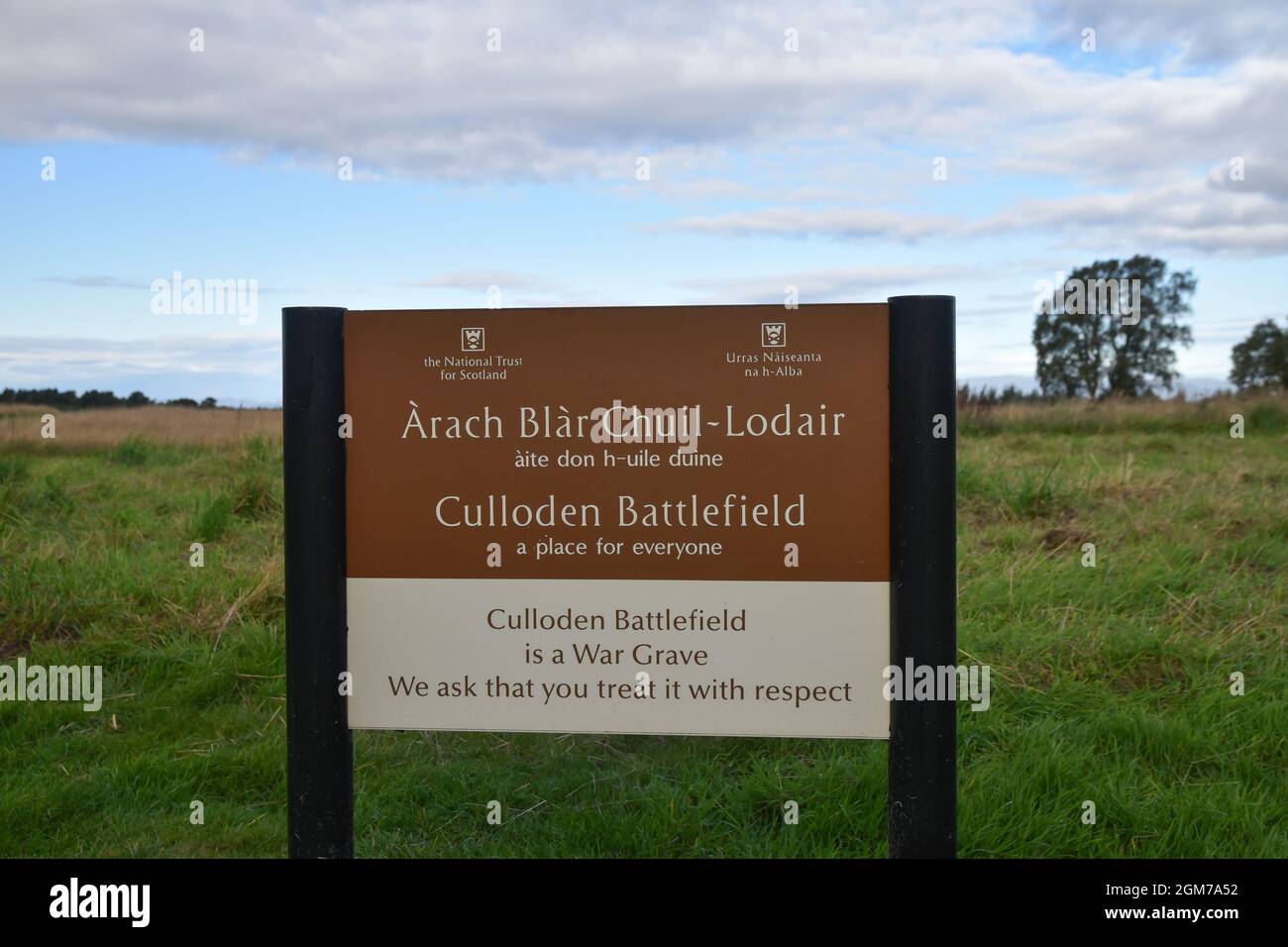 Cartello per il campo di battaglia di Culloden con sfondo sfocato di campo, alberi, cielo blu e nuvole. Foto Stock