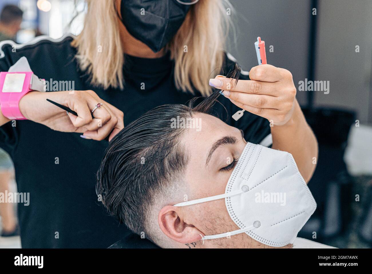 Uomo con maschera su una sedia in un parrucchiere mentre una donna gli  taglia i capelli Foto stock - Alamy