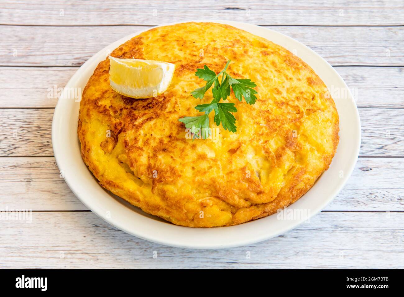Frittata di patate spagnola con prezzemolo in cima e limone per guarnire servita in un ristorante di tapas Foto Stock