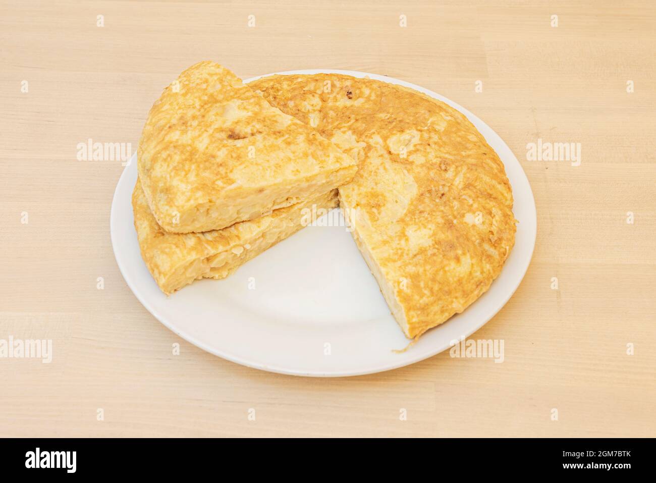 Frittata spagnola con patate e uova con una porzione separata e posta sulla parte superiore in modo che l'interno è ben impostato. Foto Stock