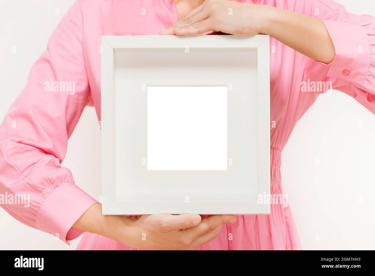 cornice d'arte bianca tenuta da donna anonima in abito rosa Foto Stock
