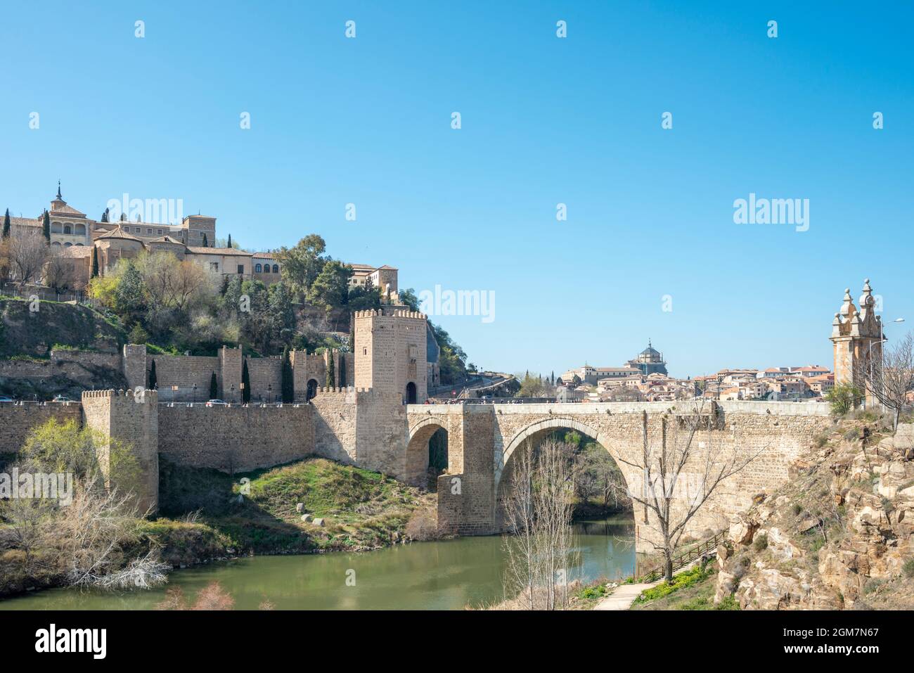 Vecchio ponte di San Martín e sullo sfondo la città monumentale di Toledo. Sotto gli archi del ponte passa placidamente il fiume Tago. Foto Stock