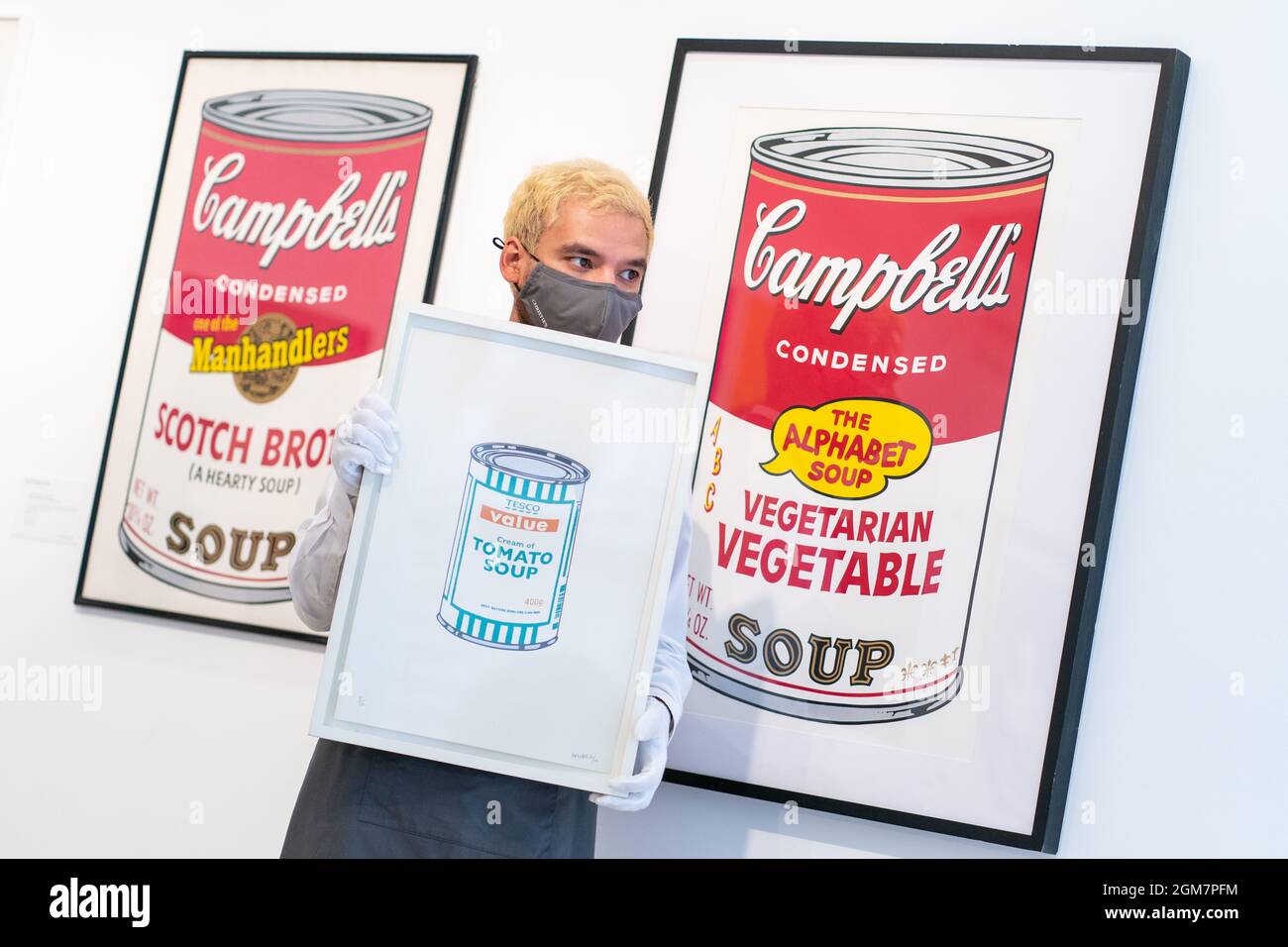 Un dipendente di Christie detiene 'Soup Can - White/Emerald/Tan' di Banksy, che si prevede di prendere £ 60,000 a £ 80,000, accanto a stampe di Andy Warhol's Campbell's Soup latts durante l'anteprima di Christie's Banksy: Non posso credere che tu moroni effettivamente acquistare questa vendita SH*t presso la sala d'asta del centro di Londra. Data foto: Venerdì 17 settembre 2021. Foto Stock