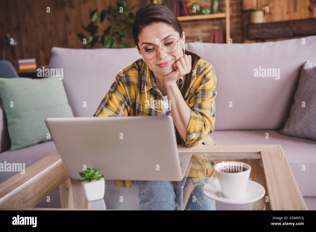 Foto di calma tranquilla felice donna guardare laptop guardare film indossare occhiali cuffie in casa Foto Stock