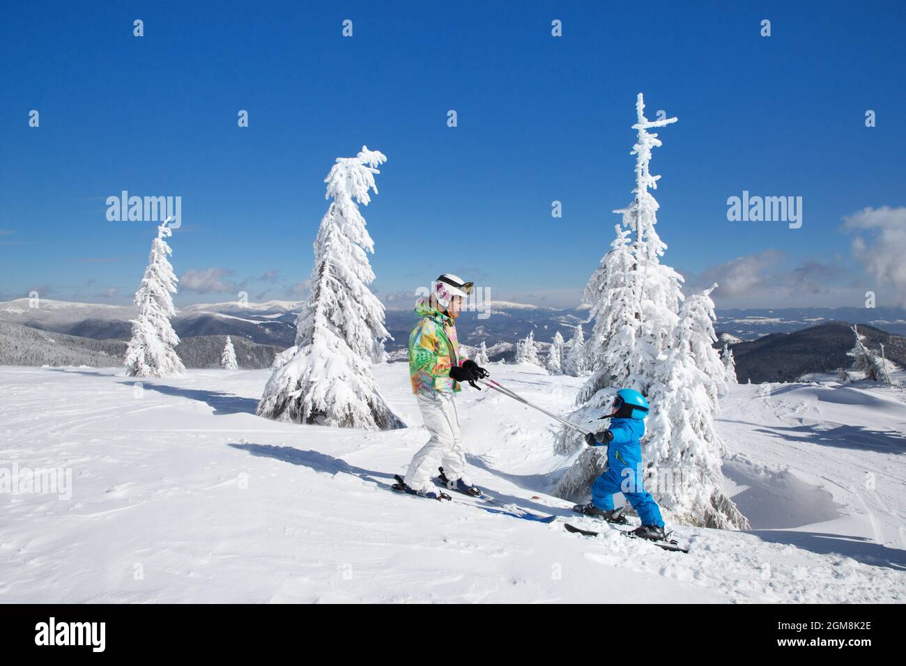 bambino e ragazza teen sci in montagna con casco, occhiali, pali. Gara di sci per bambini. Sport invernali per la famiglia. Lezione di sci per bambini nelle Alpi Foto Stock
