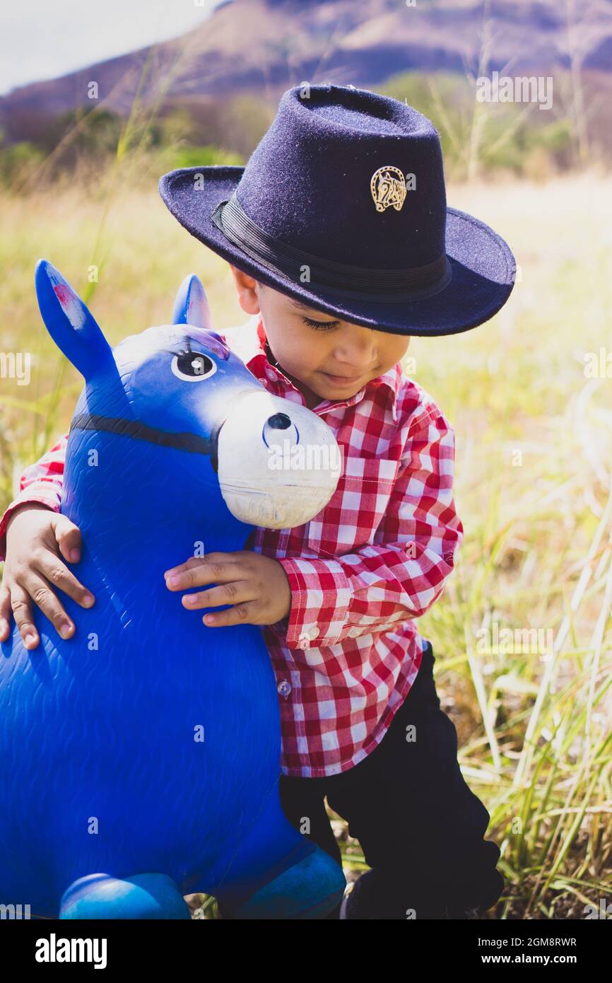 Ragazzo bianco vestito da cowboy, giocando nei boschi con il suo cavallo  giocattolo. Ritratto per bambini per giorno, moda per bambini, moda per  paese Foto stock - Alamy