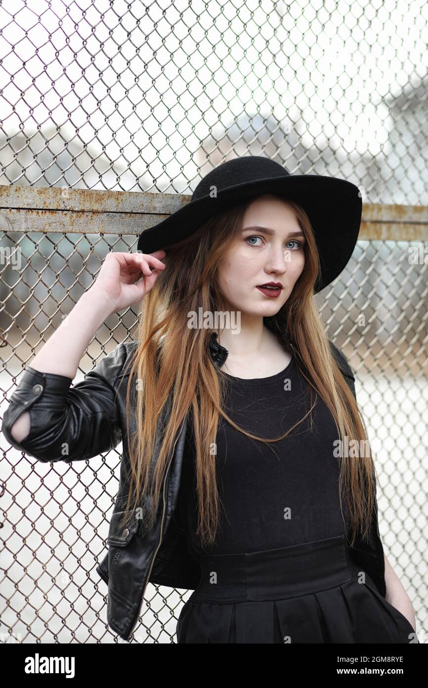 Giovane bella ragazza in un cappello e una scura di make-up all'esterno.  Ragazza in stile gotico sulla strada. Una ragazza cammina per la strada di  città in un cuoio Foto stock -
