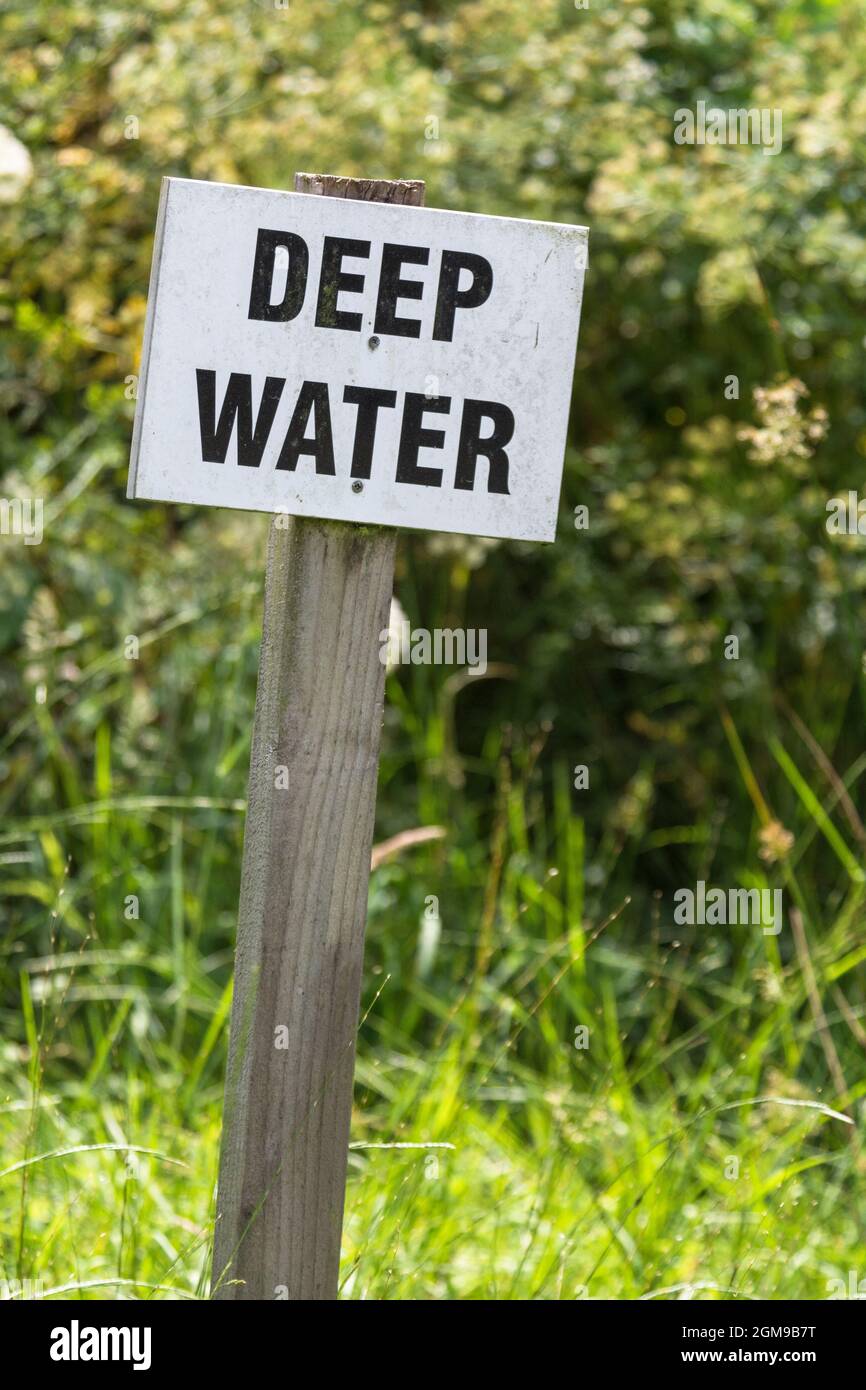 Segnale di avvertimento di acque profonde sul lato di un laghetto. Valutazione della sicurezza della metafora, analisi dei rischi, segnale di avvertimento pubblico, problemi. Foto Stock