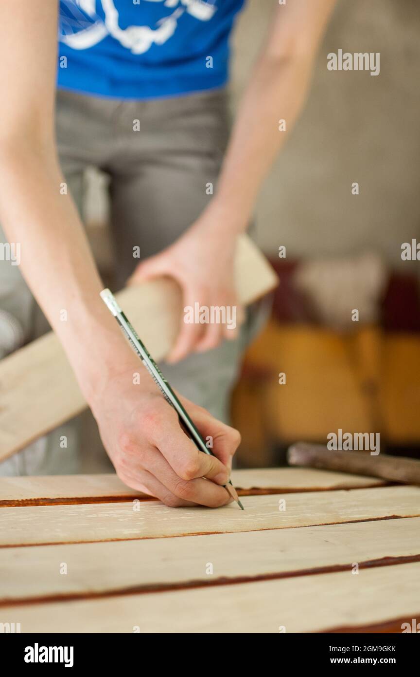 Le mani femminili stanno facendo alcuni segni sulla tavola di legno per i  fori futuri usando