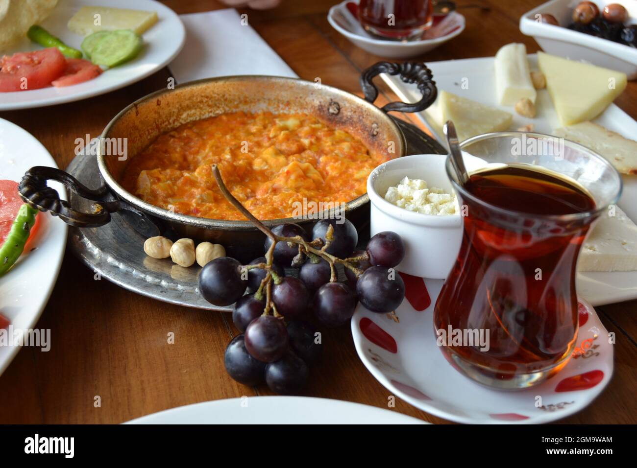 Colazione turca con tè, Menemen, nocciole, uva, olive, Formaggio tradizionale, cetriolo e fette di Tometo Foto Stock