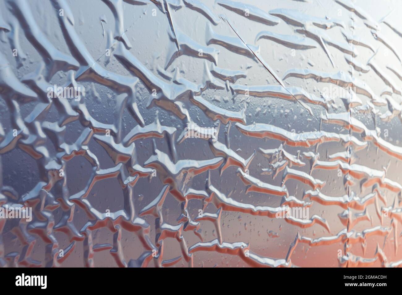 Pellicola di plastica grigia lucida con riflessi colorati incollati alla parete, foto di sfondo astratta Foto Stock