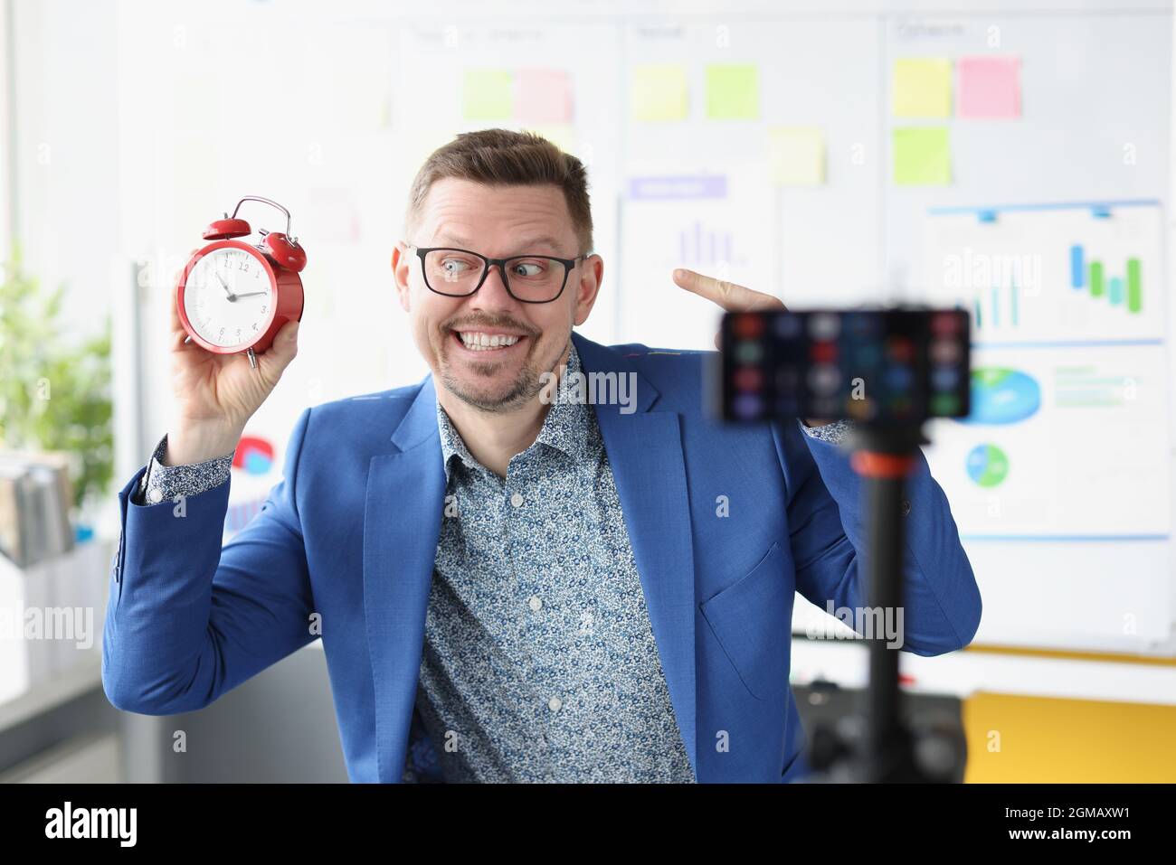 Giovane maschio blogger spara video con una sveglia rossa sulla fotocamera Foto Stock