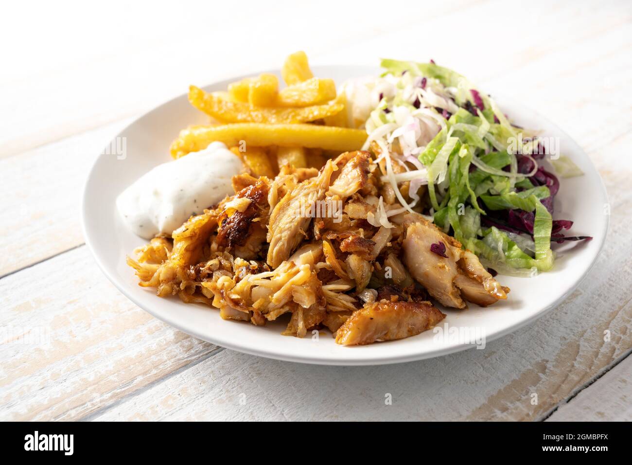 Carne di pollo arrosto da un kebab doner con patatine fritte, insalata e tzatziki tuffo su un piatto e su un tavolo di legno, spazio copia, fuoco selezionato, stretto Foto Stock
