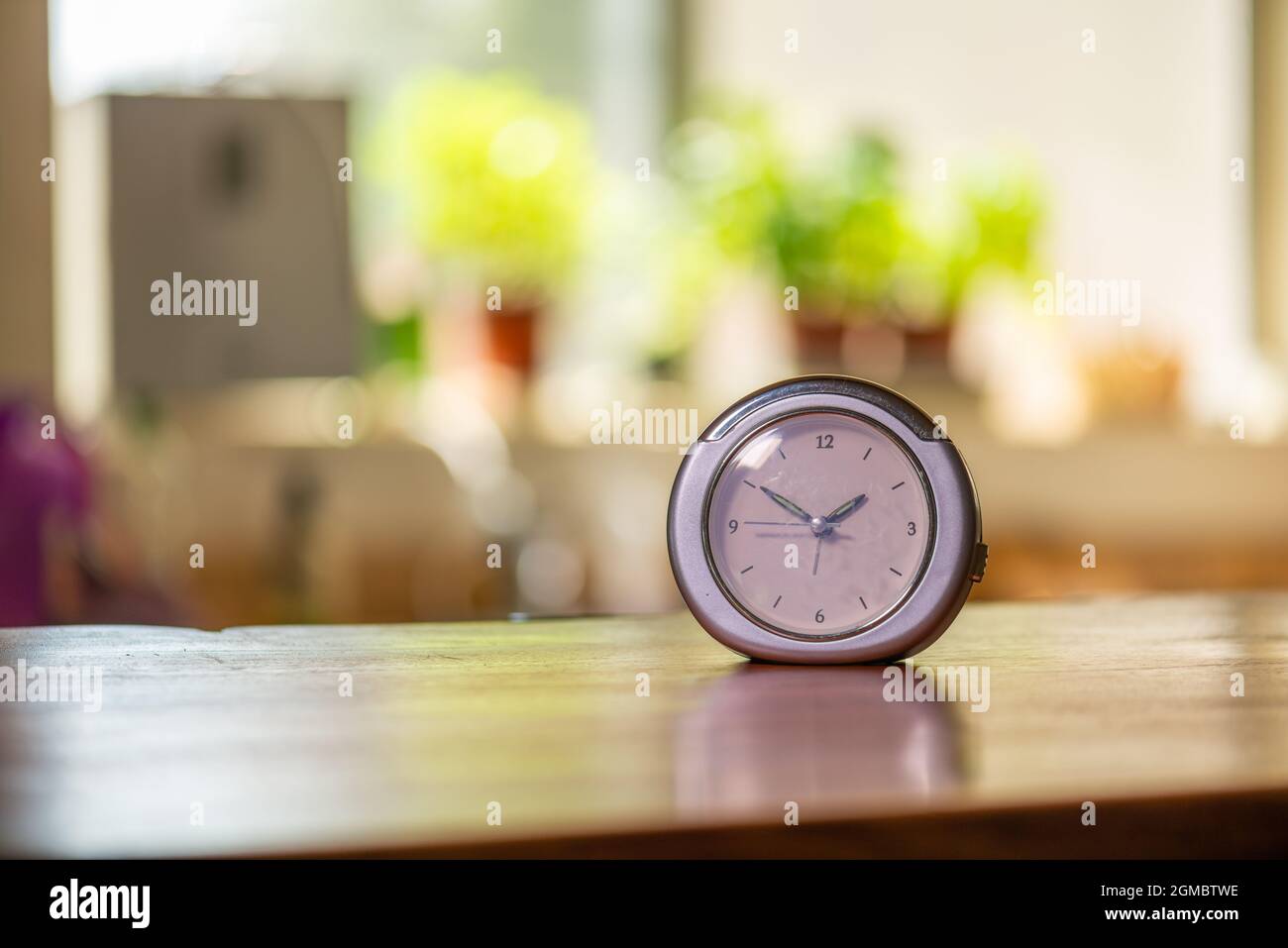 orologio su banco in legno in cucina con finestra e erbe sullo sfondo Foto Stock