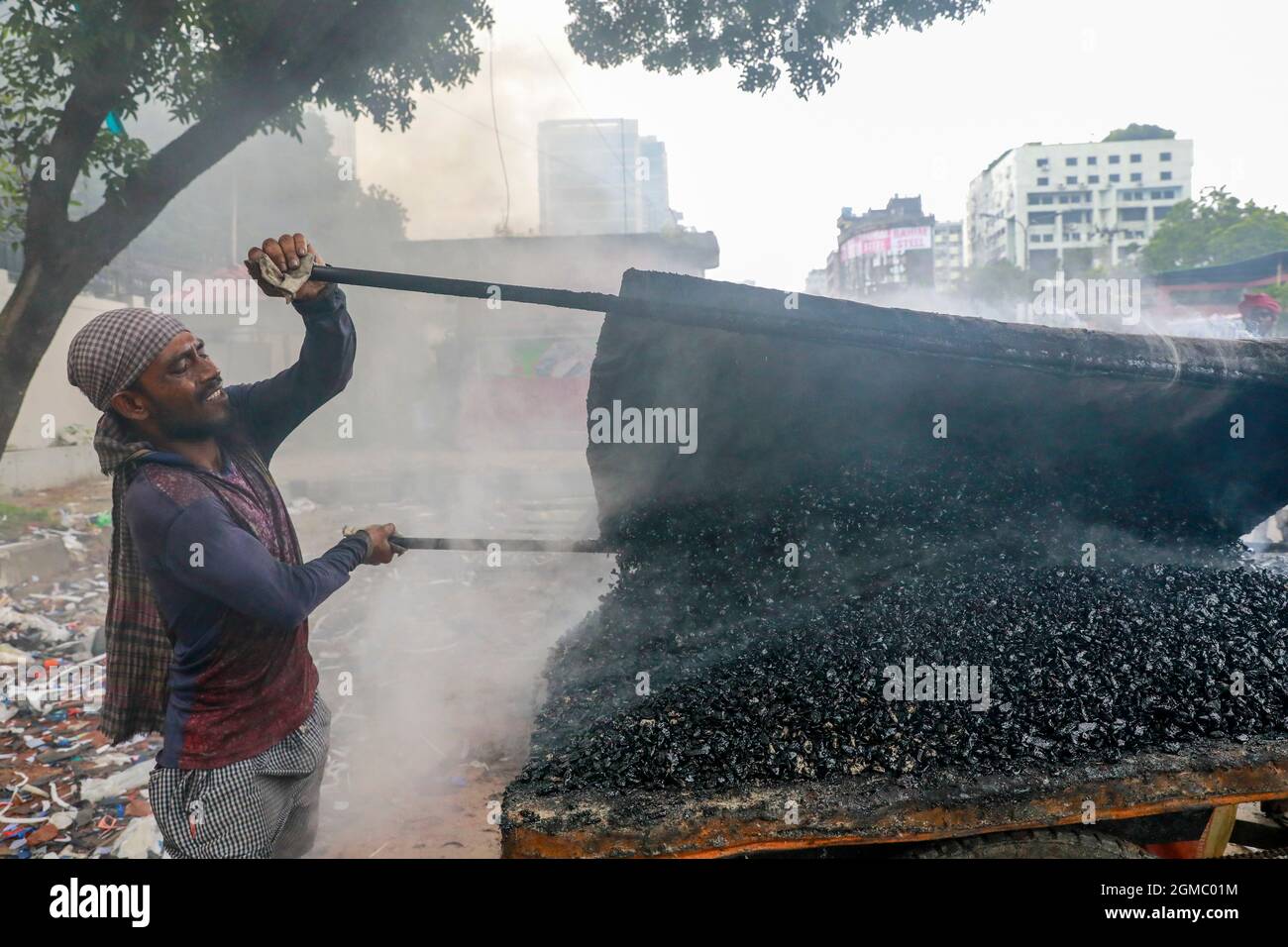 Dhaka, Bangladesh. 17 settembre 2021. DHAKA, BANGLADESH - 17 SETTEMBRE 2021: Un lavoro stradale migrante fonde i minerali di asfalto su piccole pietre per fare una miscela come parte del ripavimentamento di una strada in uno dei sobborghi di Dhaka, i dipendenti lavorano duramente diverse ore al sole per mantenere le strade e le strade della città in buone condizioni. Il 17 settembre 2021 a Dhaka, Bangladesh. (Foto di Tanvir Ahammed/ Eyepix Group) Credit: Eyepix Group/Alamy Live News Foto Stock