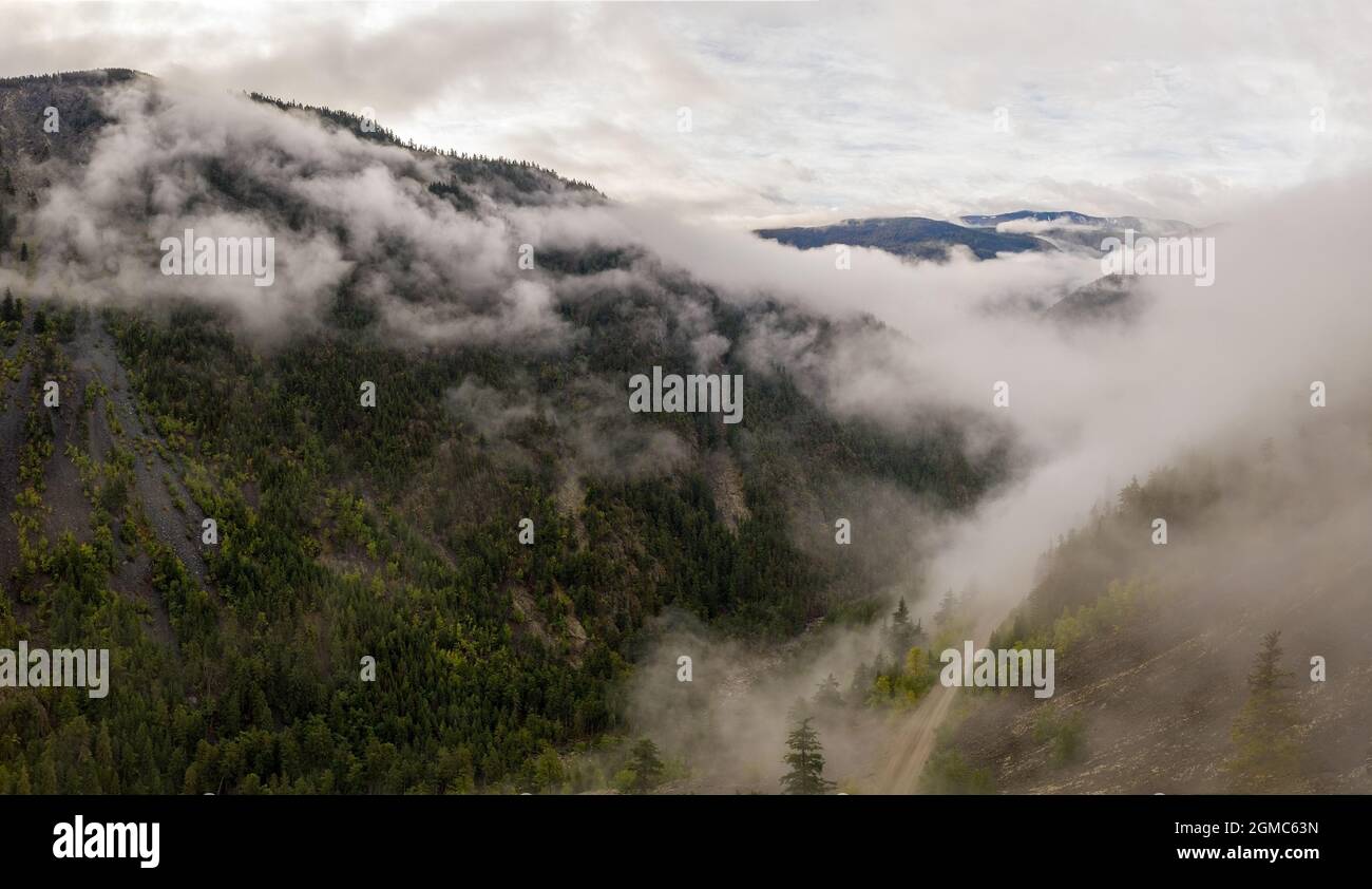 Veduta panoramica aerea del paesaggio montagnoso mozzafiato in Tweedsmuir (Sud) Parco Provinciale in una fitta nebbia che copre il m circostante Foto Stock
