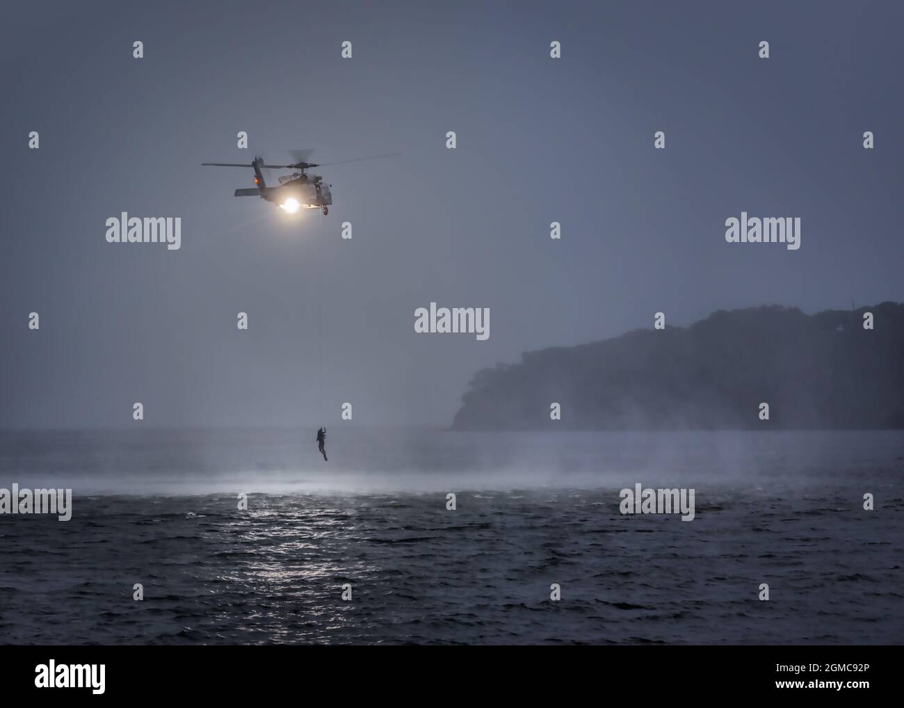 Un elicottero della Marina degli Stati Uniti MH-60 si allena dopo il sole con nuotatori di salvataggio nella Baia di Tokyo vicino a Yokosuka, Giappone. Foto Stock