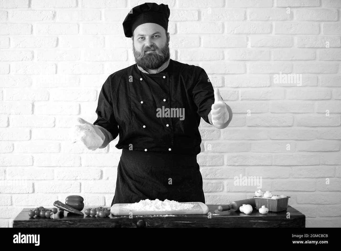 Barbuto chef lo chef prepara i pasti al tavolo in cucina Foto Stock