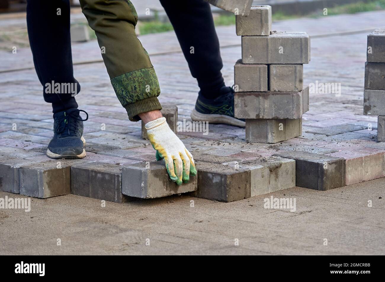 posa di lastre di pavimentazione sulla sabbia con le mani Foto Stock