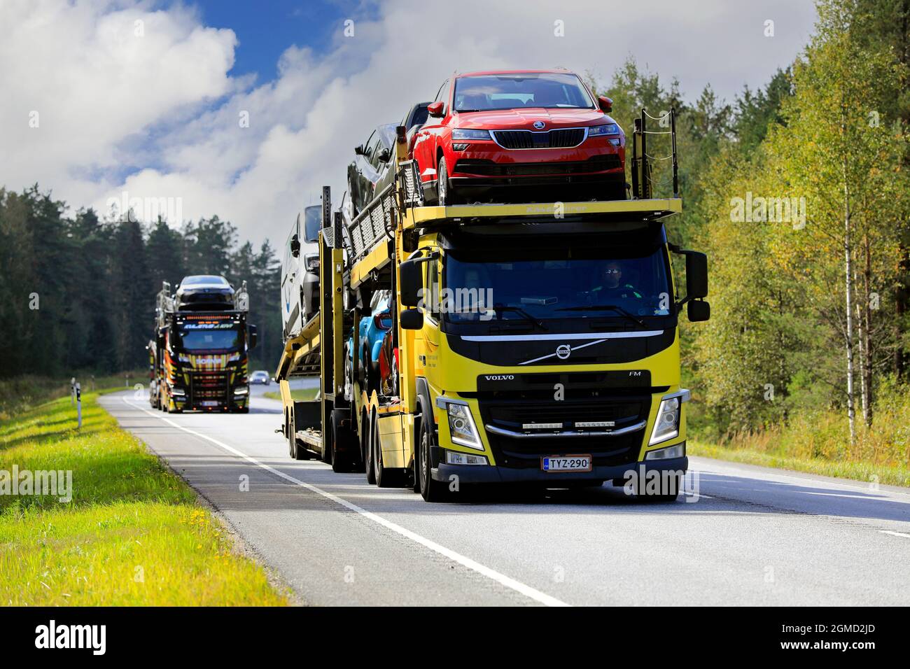 Due vettori di veicoli, il veicolo FM Volvo giallo nella parte anteriore, trasportano nuove auto sulla strada 52 dal porto di Hanko alla terraferma. Raasepori, Finlandia. 9 settembre 2021. Foto Stock