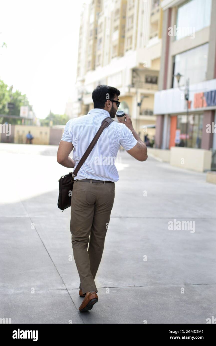 Un uomo che cammina con una tazza di caffè in formals. Foto Stock