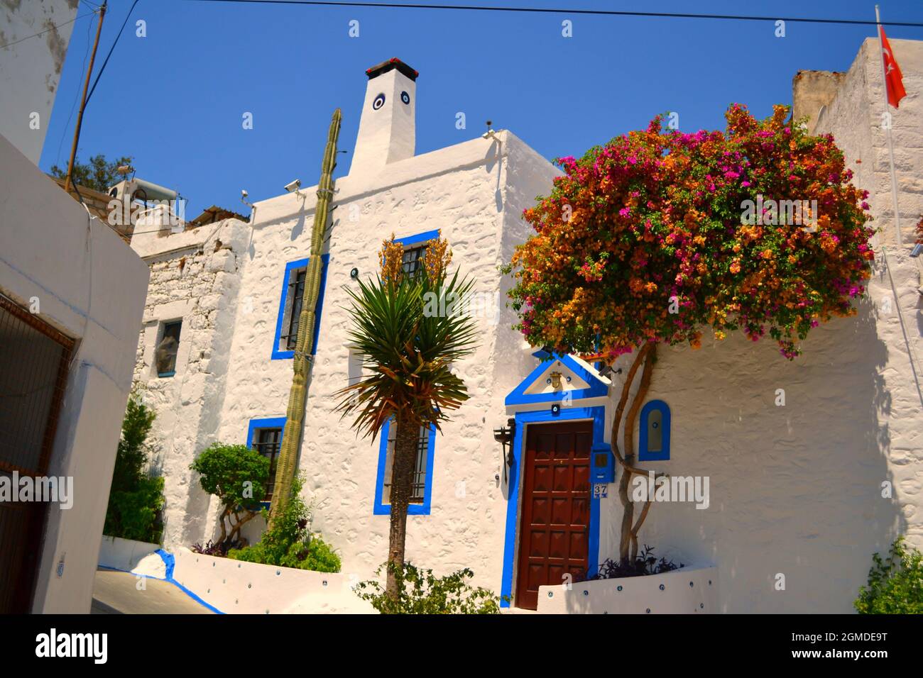 Case bianche tradizionali di Bodrum in stile mediterraneo - muro con le perle dell'occhio del male Foto Stock