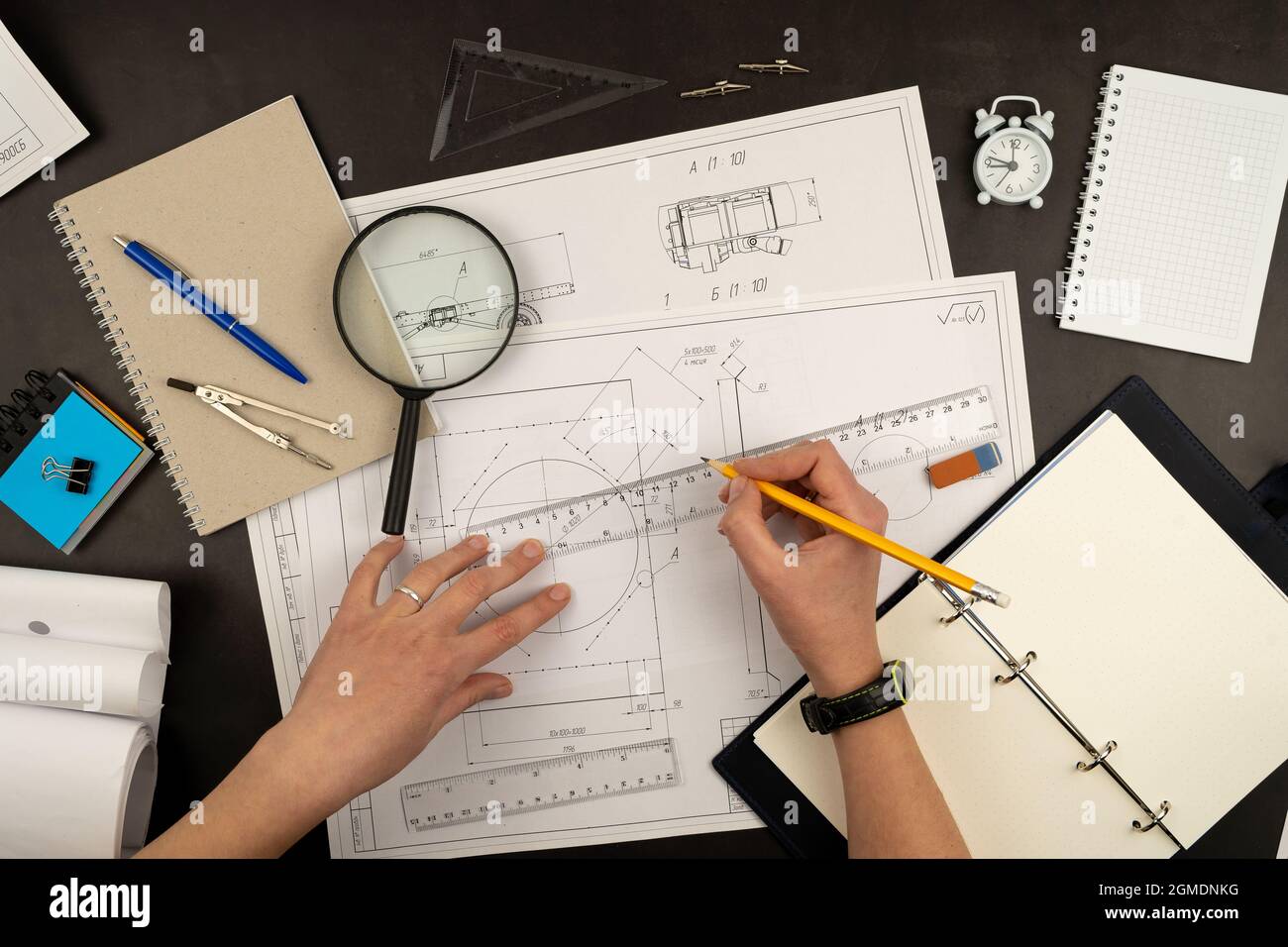 Disegno meccanico su fogli di carta. Vista dal piano portapaziente. Flusso di lavoro di un architetto, ingegnere. Scrivere e disegnare. Righello, matita, notebook Foto Stock