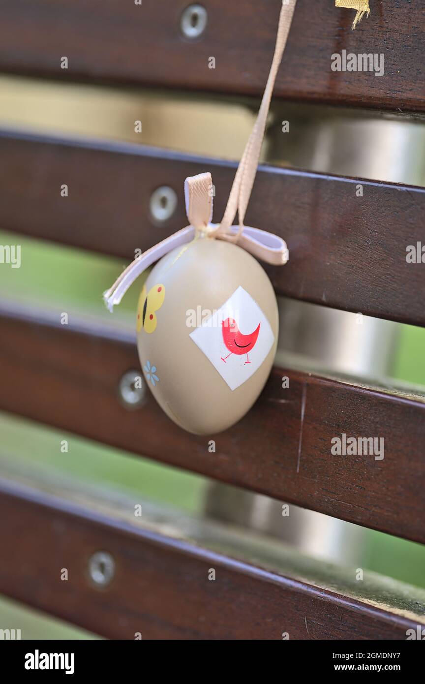 Primo piano di vista di plastica beige chiaro decorativo uovo di Pasqua legato con nastro su panca marrone scuro al campus universitario, Belfield, Dublino Irlanda Foto Stock