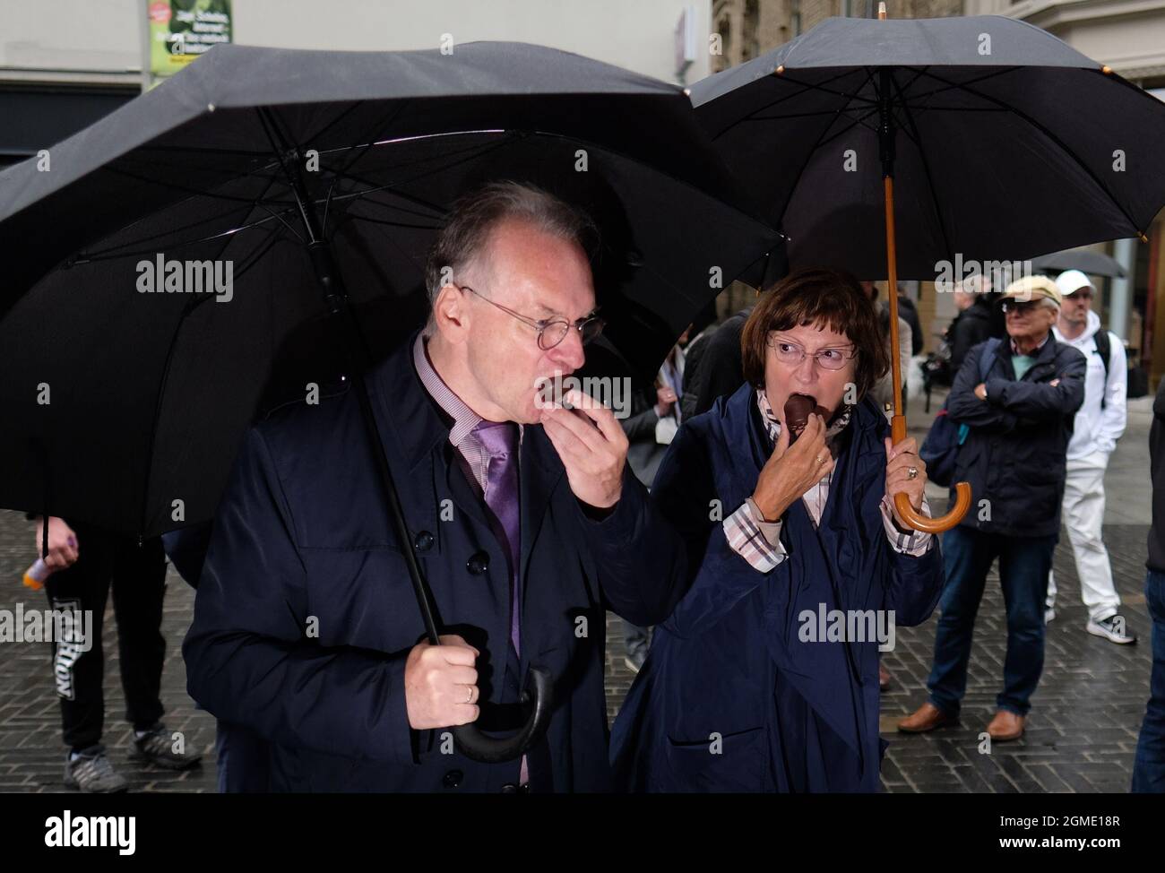Halle, Germania. 18 settembre 2021. Reiner Haseloff (CDU), Ministro Presidente della Sassonia-Anhalt, e sua moglie Gabriele Haseloff, mangiano baci di schiuma allo stand dello stato dell'Assia alla mostra 'Unity Expo 2021'. All'esposizione, i singoli stati federali si presentano in occasione della Giornata dell'unità tedesca, celebrata centralmente dall'ufficio di Haseloff come Presidente del Consiglio federale in Sassonia-Anhalt. Credit: dpa/dpa-Zentralbild/dpa/Alamy Live News Foto Stock