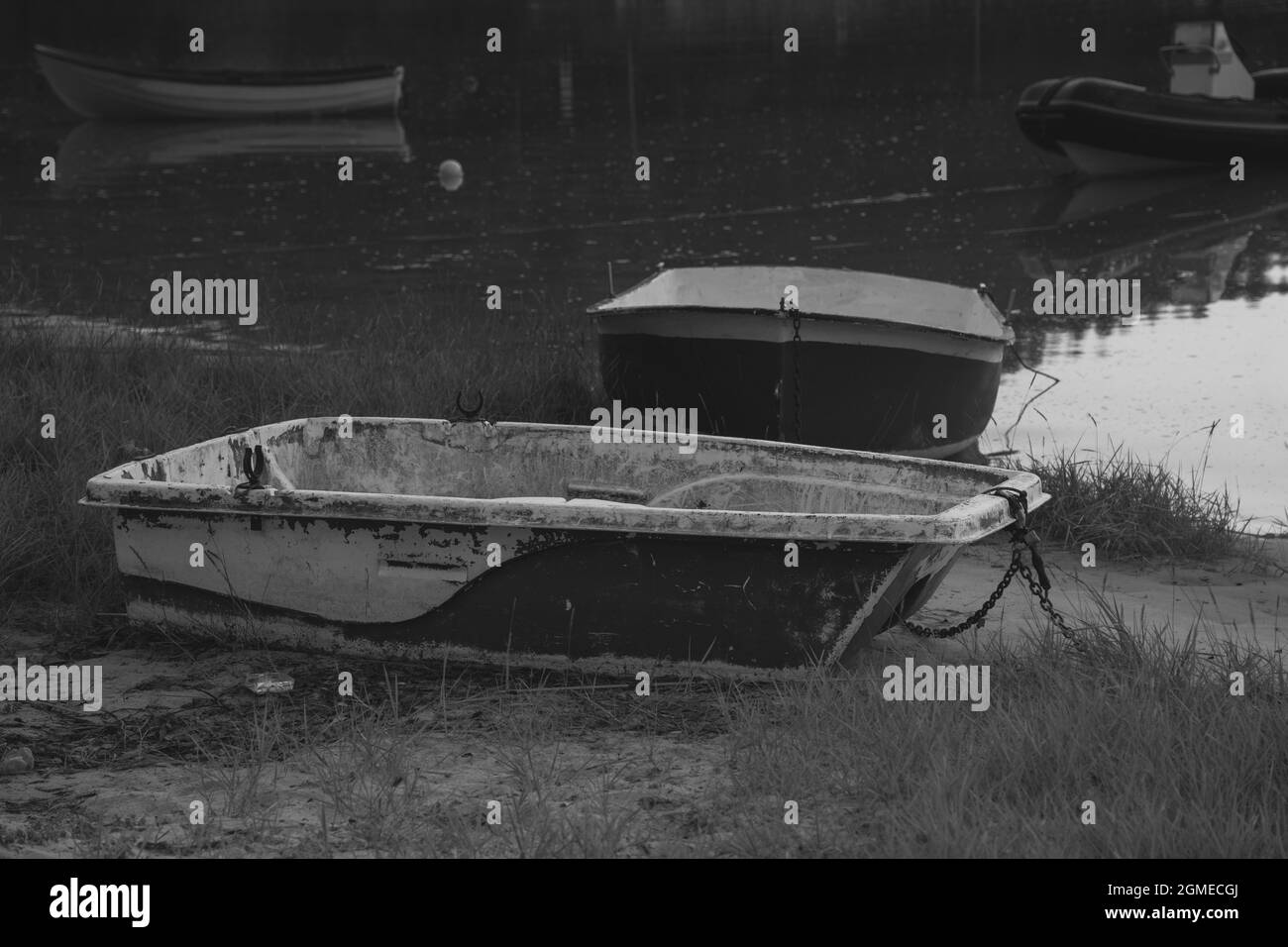 Foto in scala di grigi delle vecchie barche sporche sulla riva di un lago Foto Stock