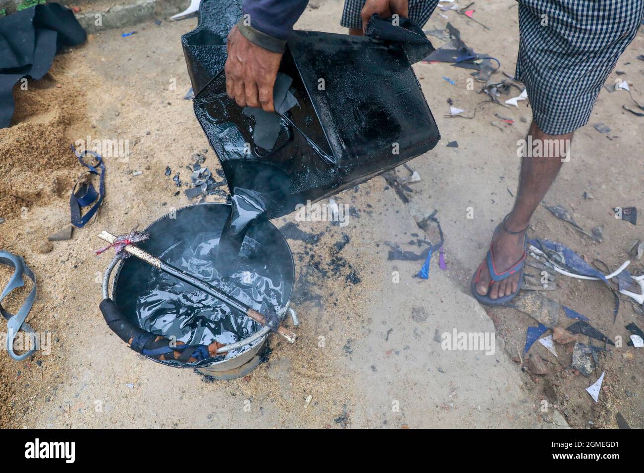 DHAKA, BANGLADESH - 17 SETTEMBRE 2021: Un lavoro stradale migrante fonde i minerali di asfalto su piccole pietre per fare una miscela come parte del ripavimentamento di una strada in uno dei sobborghi di Dhaka, i dipendenti lavorano duramente diverse ore al sole per mantenere le strade e le strade della città in buone condizioni. Il 17 settembre 2021 a Dhaka, Bangladesh. (Foto di Tanvir Ahammed/ Eyepix Group/Sipa USA) Foto Stock