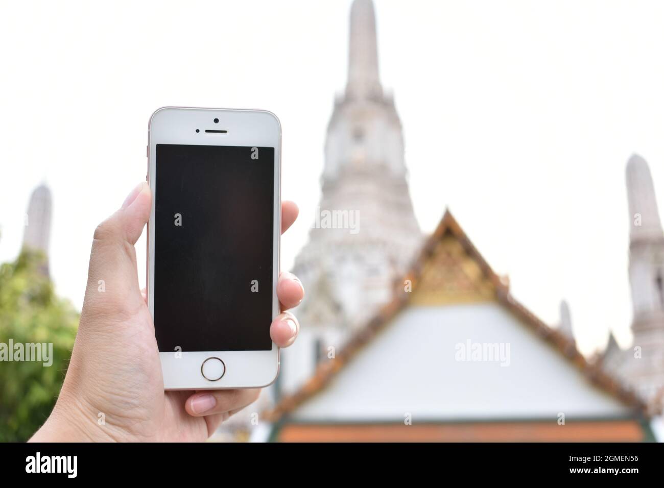 Tenere a mano smartphone mock-up trovare il segnale GPS e tempio tailandese in background Foto Stock