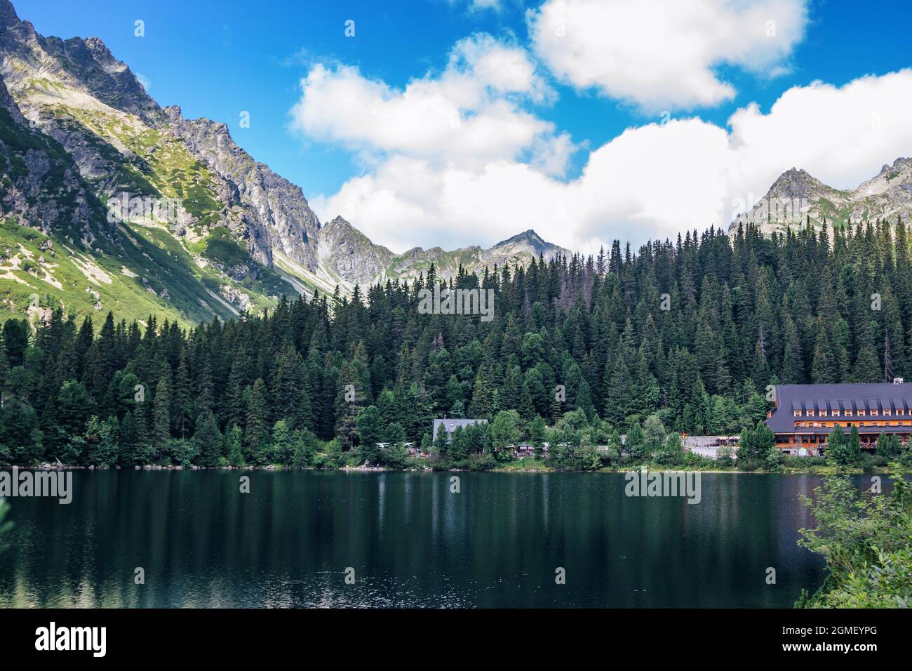 Bellissimo paesaggio estivo di alti Tatra, Slovacchia – lago di Poprad, foresta lussureggiante, montagne e nuvole bianche sul cielo Foto Stock
