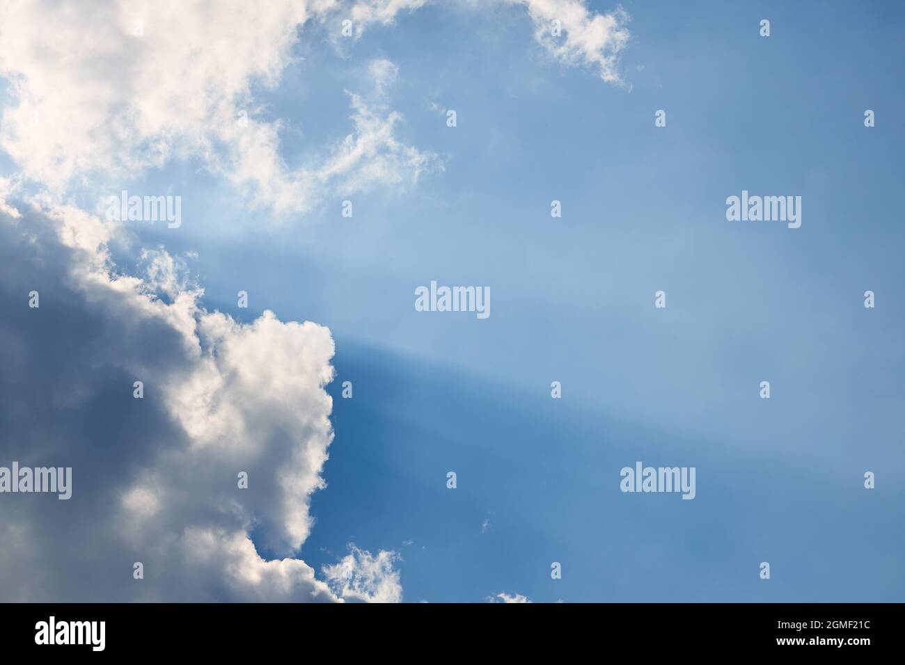 Nuvola nel cielo con ombra e raggi solari primo piano su cielo blu chiaro diagonale composizione con copyspace. Potere, spiritualità, religione, speranza e. Foto Stock