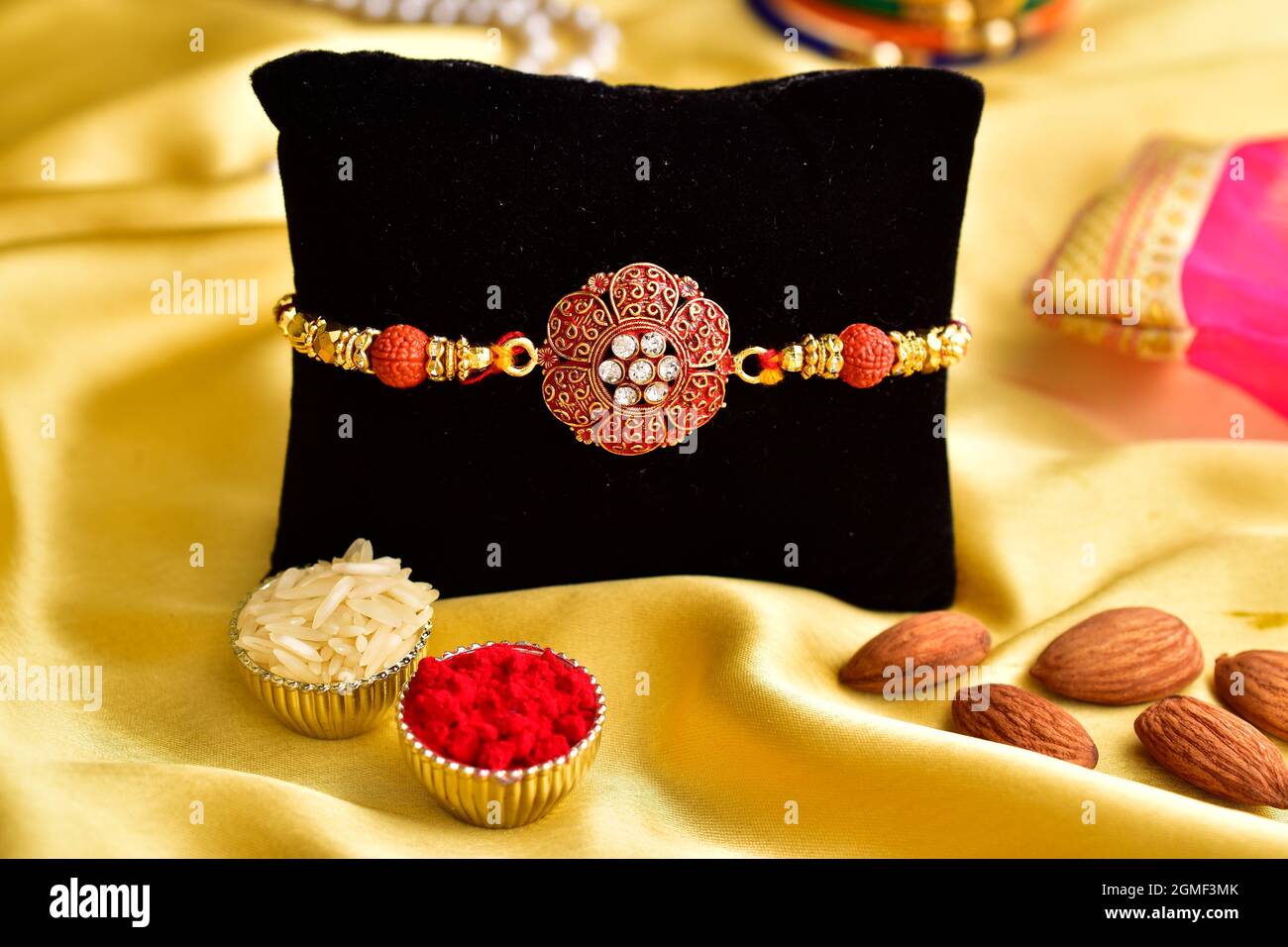 Rakhi con roli Chawal e mandorle su sfondo giallo di seta Foto Stock
