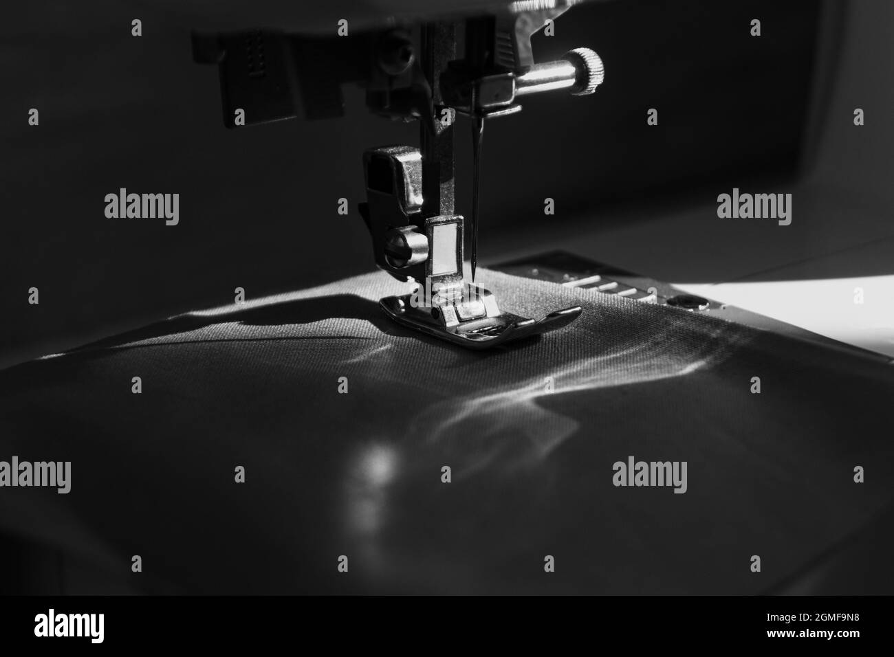 macchina da cucire vista ravvicinata con luce naturale del sole, moda lenta e concetto di cucito domestico in bianco e nero Foto Stock
