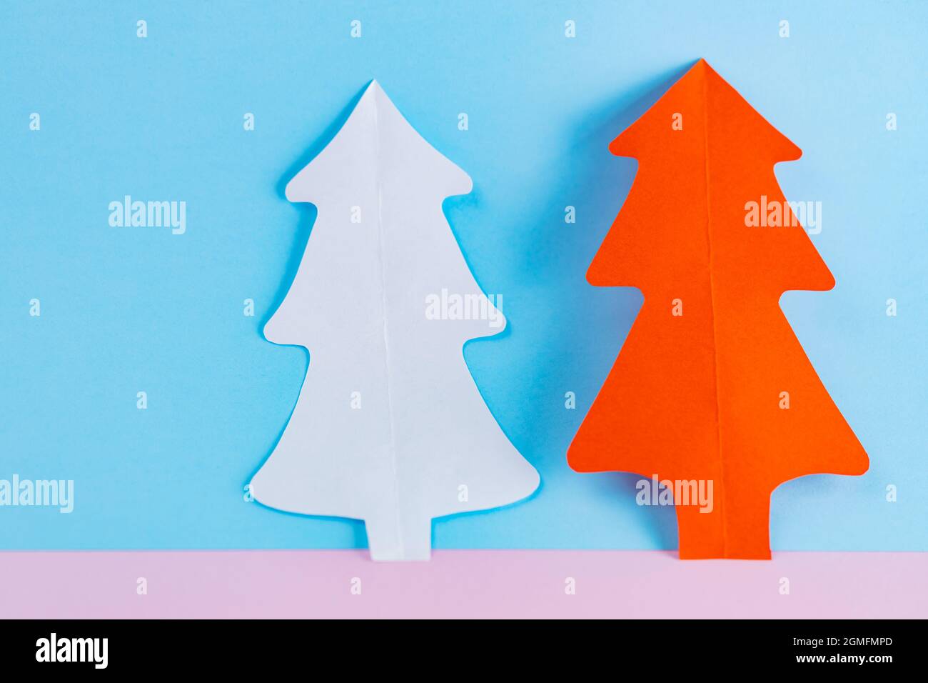 Carta alberi di Natale su sfondo blu-rosa. Alberi di natale di carta bianca e rossa. Concetto minimo di Natale Foto Stock