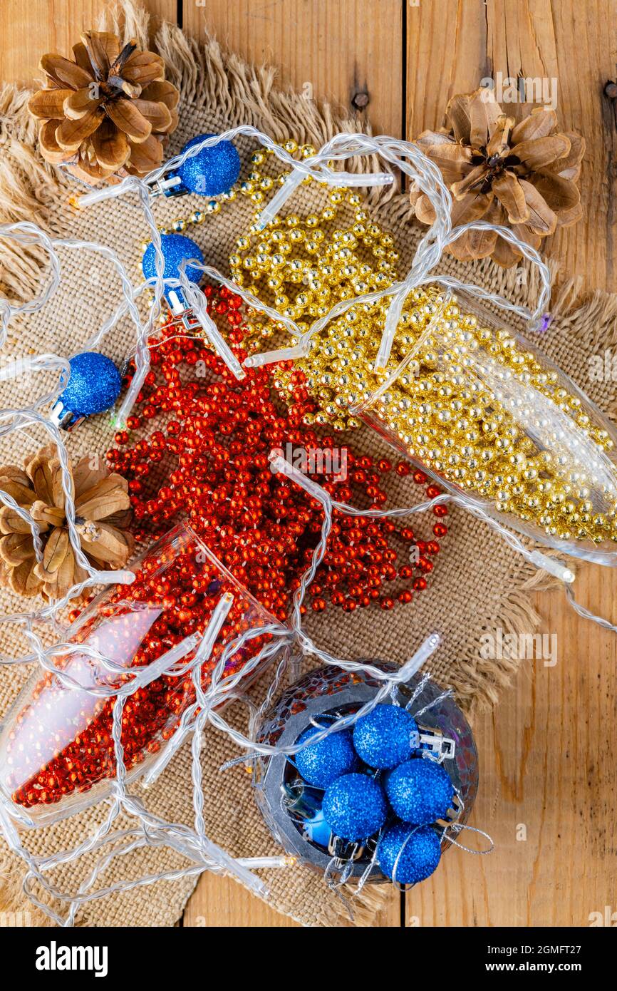 Due bicchieri di champagne con perle natalizie. Palle di Natale e decorazioni su sackcloth. Coni di pino e perle multicolore su sfondo di legno. Superiore Foto Stock